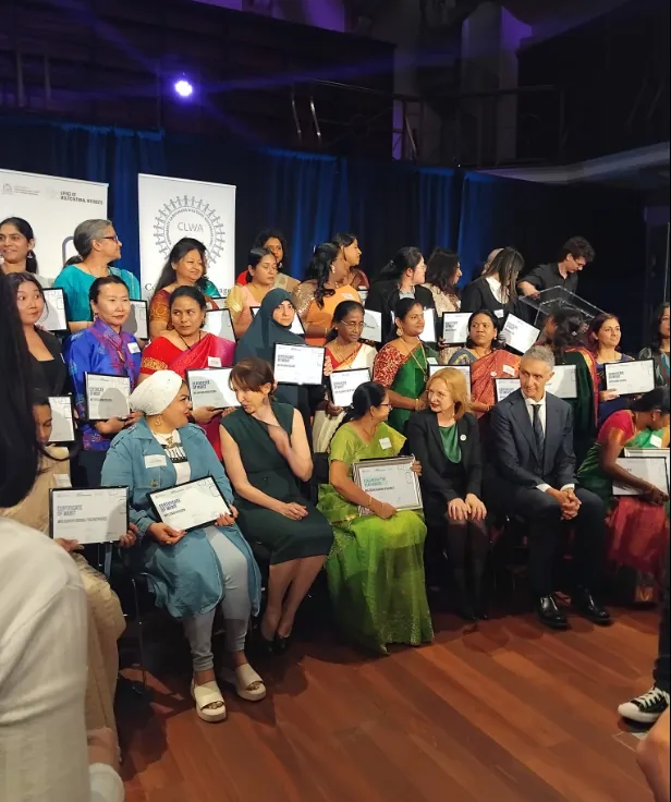 A large group on stage holding certificates at a ceremony